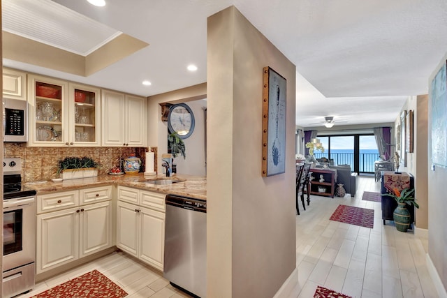 kitchen featuring ceiling fan, sink, stainless steel appliances, and cream cabinetry