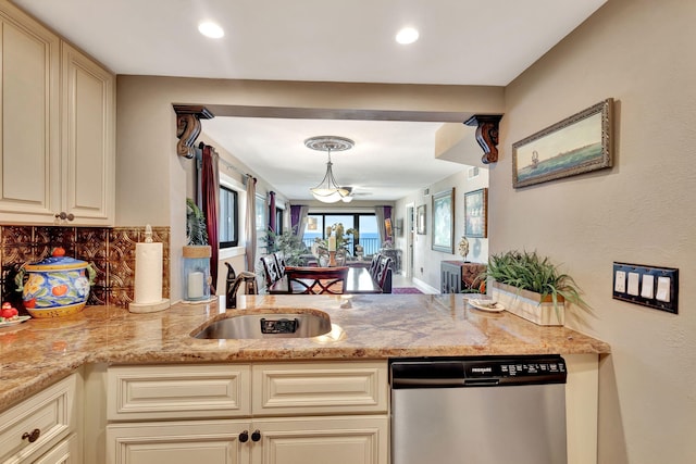 kitchen featuring decorative backsplash, stainless steel dishwasher, sink, cream cabinetry, and hanging light fixtures