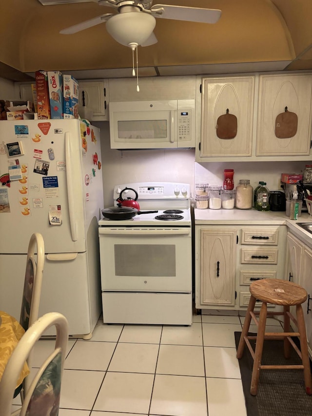 kitchen with ceiling fan, cream cabinets, light tile patterned floors, and white appliances