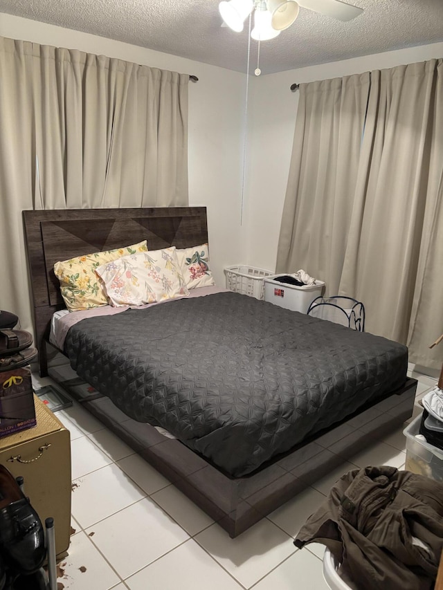 bedroom with a textured ceiling, ceiling fan, and light tile patterned flooring