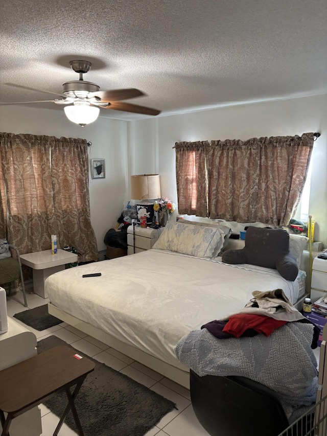 tiled bedroom with ceiling fan and a textured ceiling