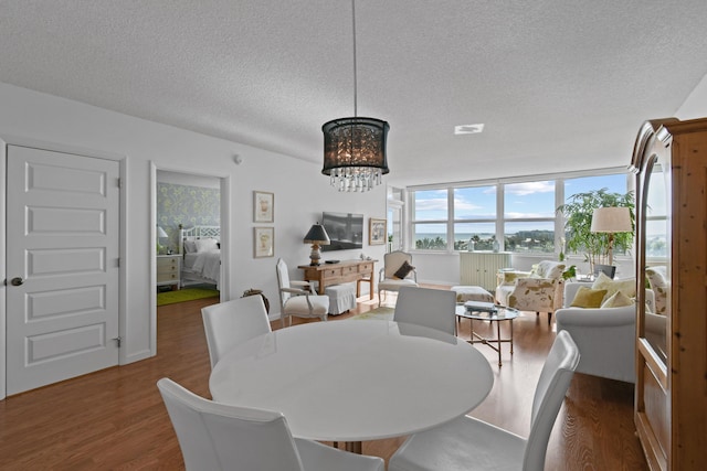 dining area with a textured ceiling, floor to ceiling windows, a chandelier, and dark hardwood / wood-style floors