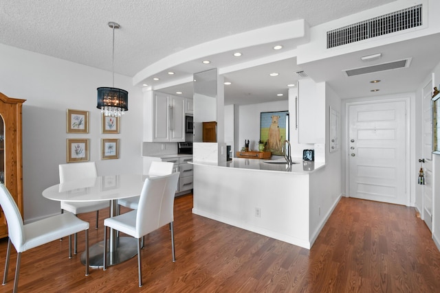 dining room with dark hardwood / wood-style flooring, sink, a textured ceiling, and a chandelier