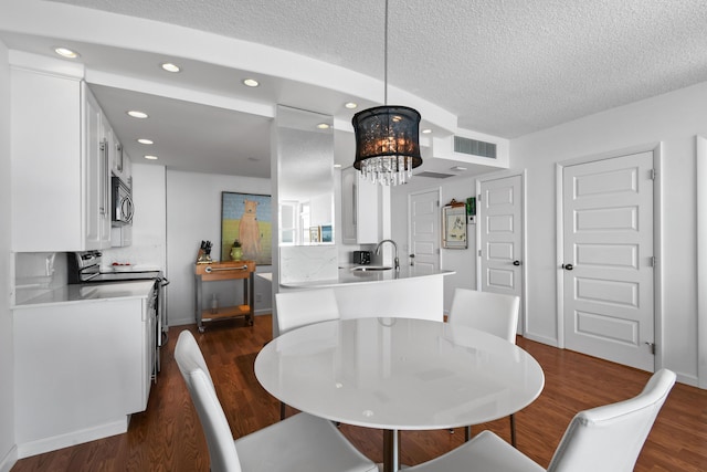 dining space with dark hardwood / wood-style flooring, sink, a textured ceiling, and an inviting chandelier