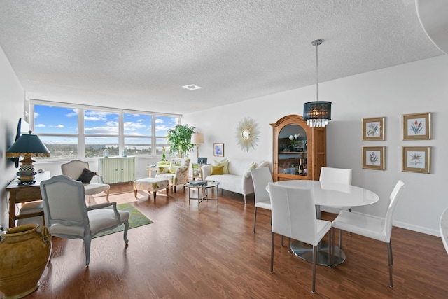 dining space featuring dark wood-type flooring, a textured ceiling, and an inviting chandelier