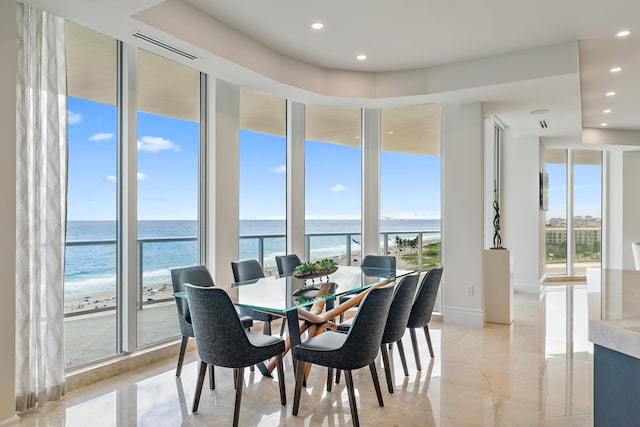 dining area with a wall of windows, a water view, and plenty of natural light