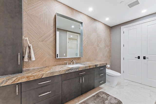 bathroom with vanity, toilet, and tile walls