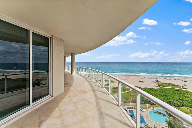 balcony featuring a view of the beach and a water view