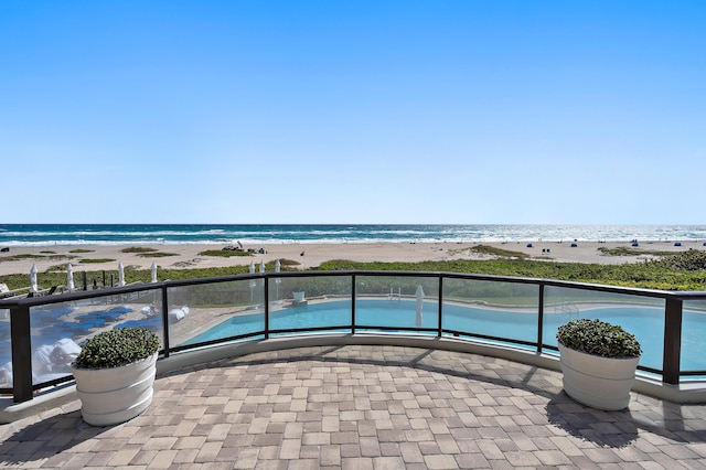 view of swimming pool featuring a water view and a view of the beach