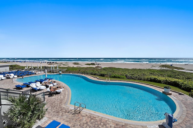 view of swimming pool with a water view and a view of the beach