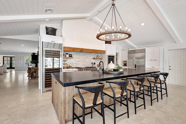 kitchen with beam ceiling, white cabinets, stainless steel appliances, and beverage cooler