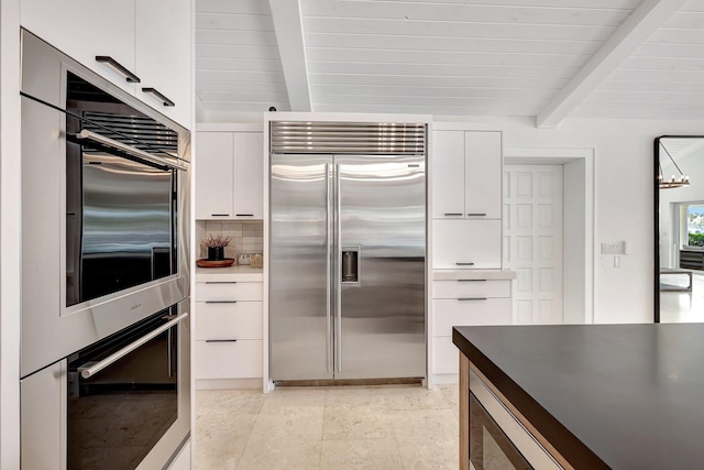 kitchen featuring beam ceiling, white cabinets, and appliances with stainless steel finishes