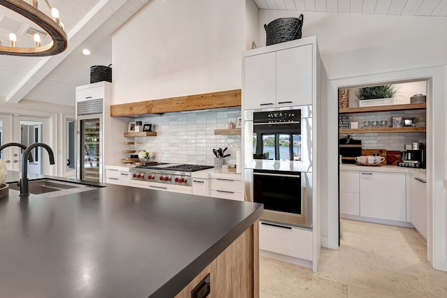 kitchen featuring backsplash, stainless steel appliances, sink, lofted ceiling with beams, and white cabinetry