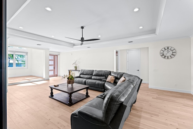 living room with a raised ceiling, ceiling fan, and light hardwood / wood-style floors