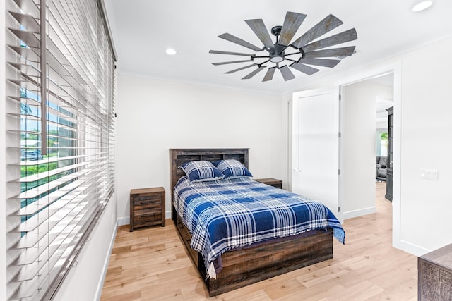 bedroom with multiple windows, hardwood / wood-style floors, ceiling fan, and ornamental molding