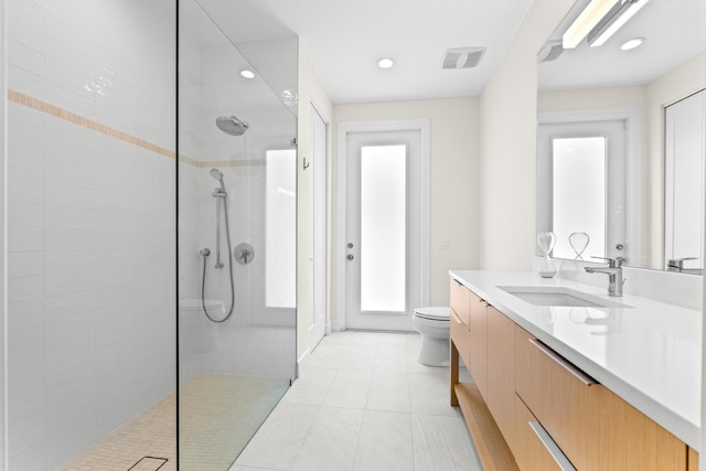 bathroom featuring a tile shower, tile patterned floors, vanity, and toilet