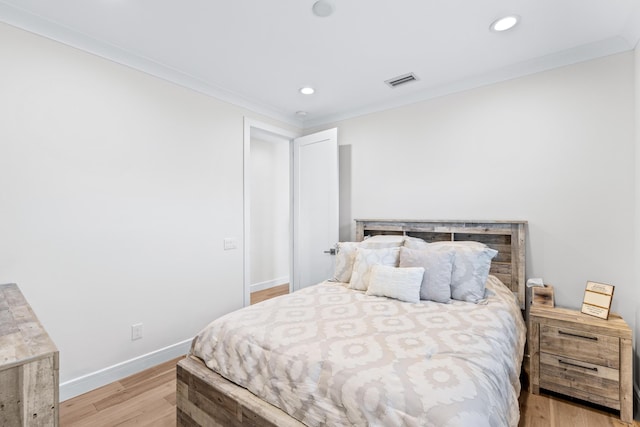 bedroom with crown molding and light hardwood / wood-style floors