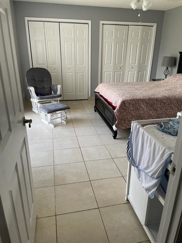 bedroom with a textured ceiling, a closet, tile patterned floors, and ceiling fan