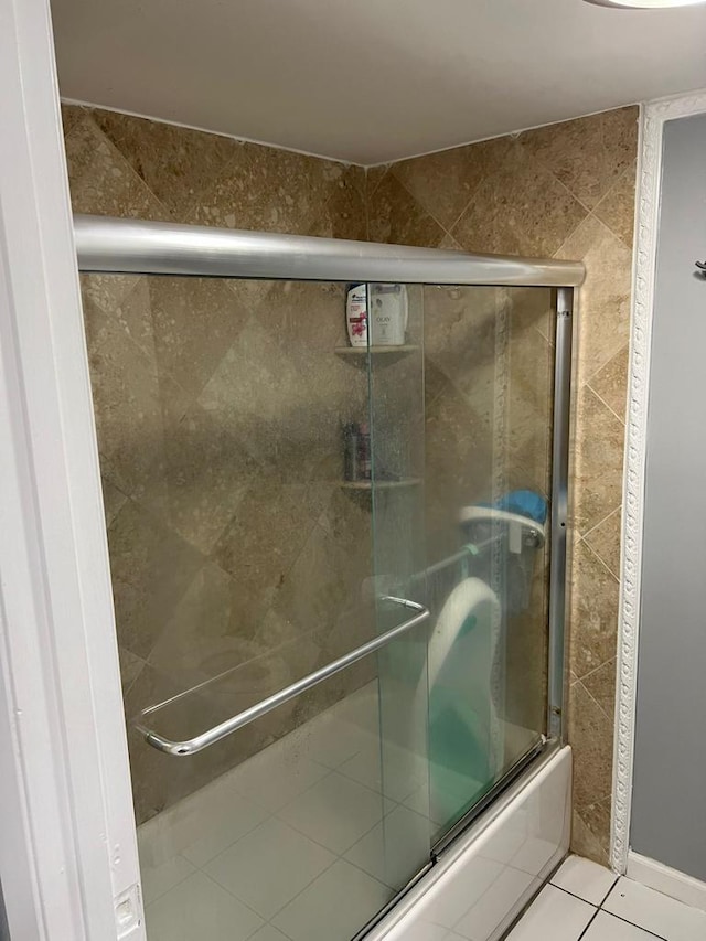 bathroom with combined bath / shower with glass door and tile patterned floors