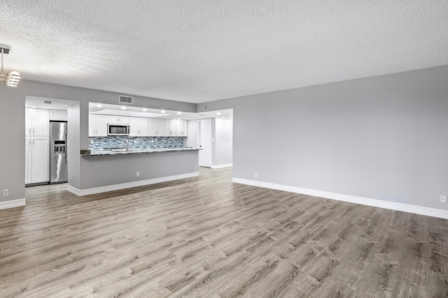 unfurnished living room featuring light hardwood / wood-style floors and a textured ceiling