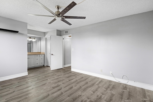 unfurnished bedroom with ensuite bathroom, ceiling fan, light hardwood / wood-style floors, and a textured ceiling