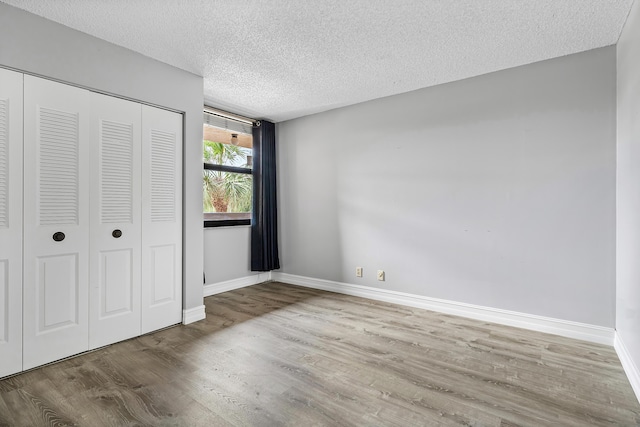 unfurnished bedroom with a textured ceiling, light hardwood / wood-style floors, and a closet