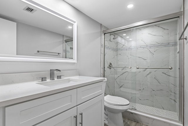 bathroom featuring vanity, toilet, and a shower with shower door