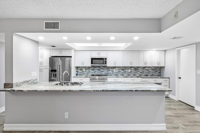 kitchen featuring kitchen peninsula, appliances with stainless steel finishes, white cabinetry, and sink