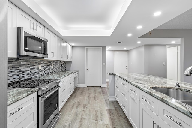 kitchen featuring sink, light hardwood / wood-style flooring, light stone countertops, white cabinetry, and stainless steel appliances