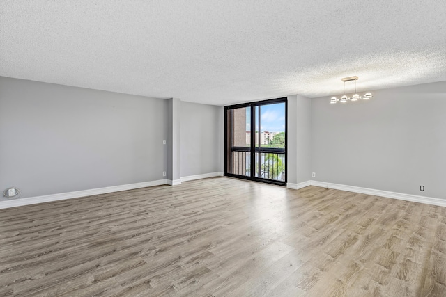 unfurnished room featuring floor to ceiling windows, light hardwood / wood-style floors, a textured ceiling, and a chandelier