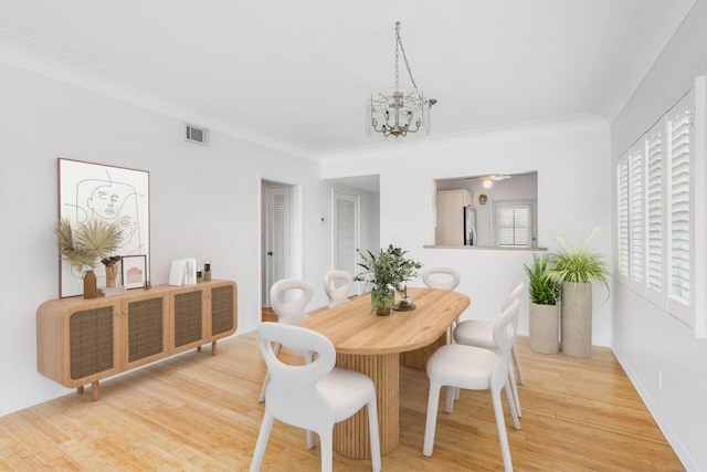 dining area featuring ornamental molding, a notable chandelier, and light hardwood / wood-style floors