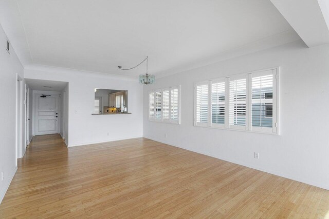 dining area with crown molding, light wood-type flooring, and an inviting chandelier