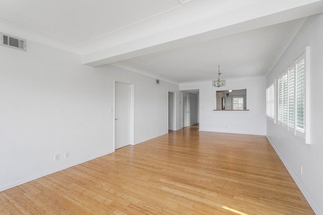 unfurnished living room with an inviting chandelier, crown molding, and light wood-type flooring