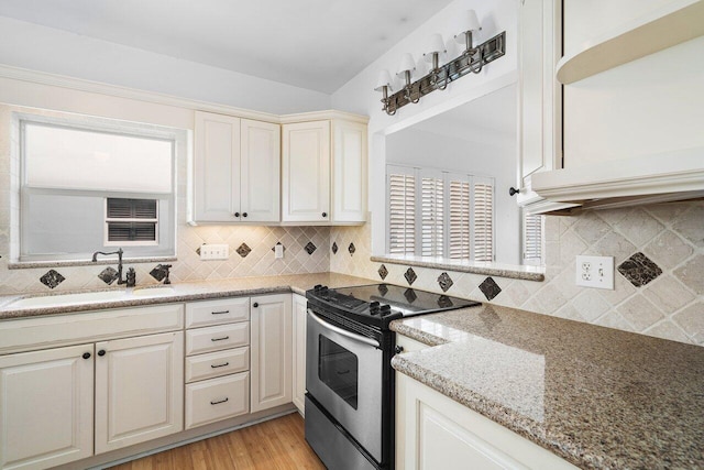 kitchen with sink, stainless steel electric range, tasteful backsplash, light stone countertops, and light wood-type flooring