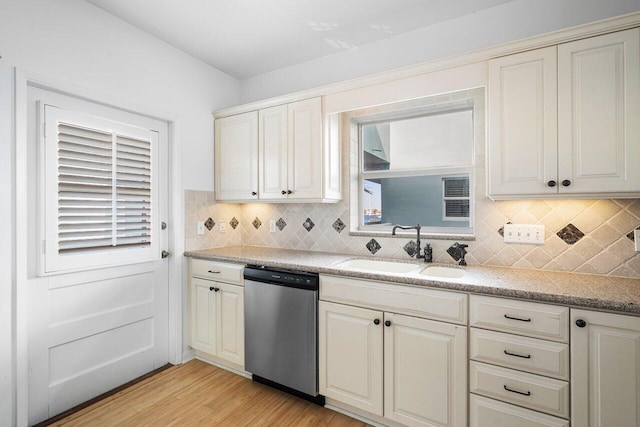 kitchen featuring sink, stainless steel dishwasher, light stone counters, and light wood-type flooring