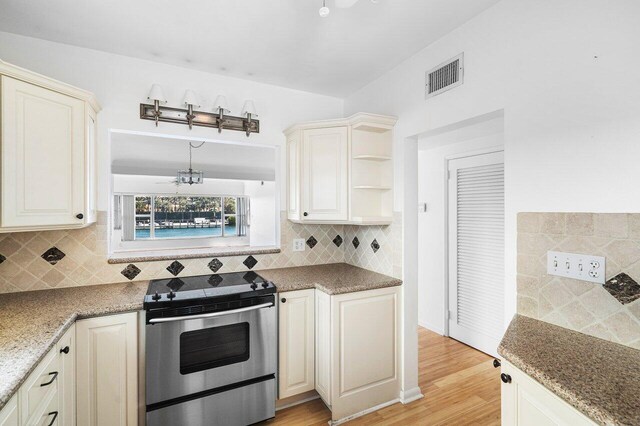 kitchen with stone counters, backsplash, electric range, a chandelier, and light wood-type flooring