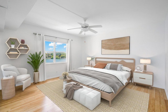 bedroom featuring ceiling fan, a water view, and light hardwood / wood-style flooring