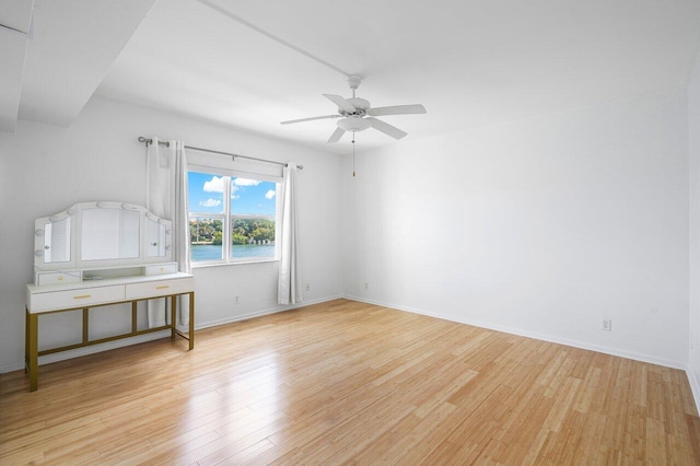 empty room featuring light hardwood / wood-style floors, ceiling fan, and a water view