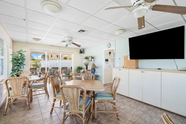 tiled dining area featuring ceiling fan and a drop ceiling