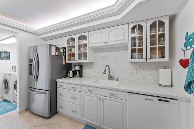 kitchen featuring white dishwasher, sink, stainless steel fridge with ice dispenser, white cabinetry, and washing machine and clothes dryer