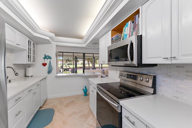 kitchen with light tile patterned floors, tasteful backsplash, a tray ceiling, white cabinets, and appliances with stainless steel finishes