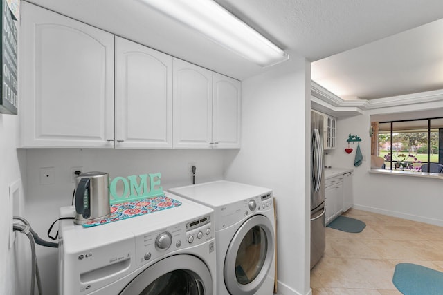 laundry room featuring washer and clothes dryer, cabinets, light tile patterned floors, and a textured ceiling