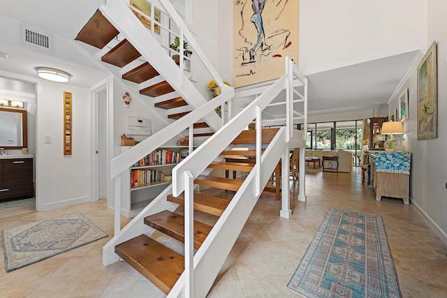 stairway with tile patterned floors and crown molding