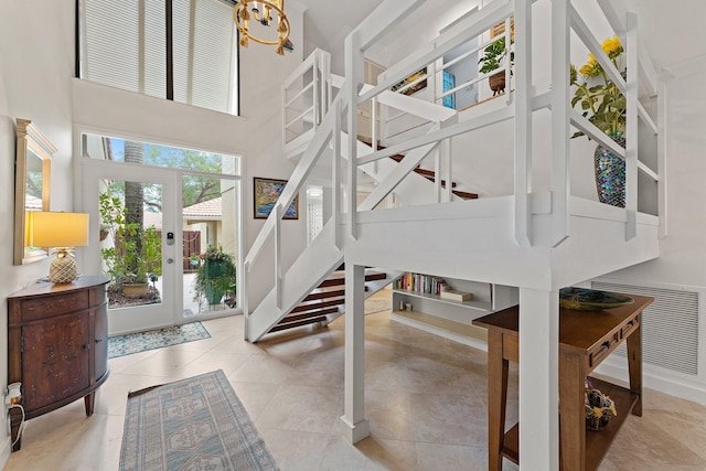 stairs featuring tile patterned flooring, a high ceiling, and an inviting chandelier