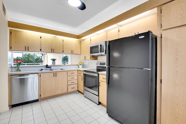 kitchen featuring light tile patterned flooring, sink, stainless steel appliances, and light brown cabinetry