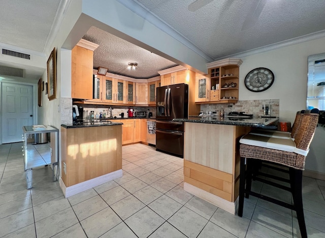 kitchen featuring black refrigerator with ice dispenser, a kitchen breakfast bar, decorative backsplash, dark stone countertops, and kitchen peninsula