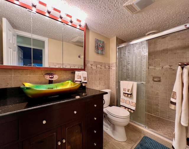 bathroom featuring tile patterned flooring, an enclosed shower, toilet, vanity, and tile walls