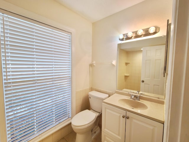 bathroom featuring vanity, tile walls, and toilet