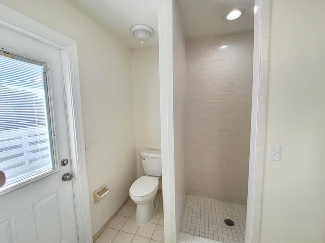 bathroom with tile patterned flooring, a tile shower, and toilet