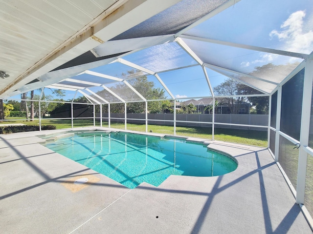 view of swimming pool featuring a patio, a yard, and glass enclosure